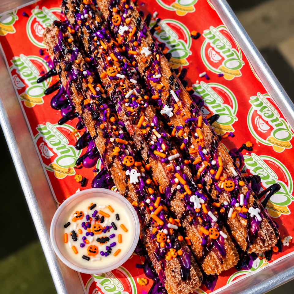 Crispy churro sticks drizzled with purple and black icing, covered in Halloween sprinkles, with a dipping cup on a branded tray.