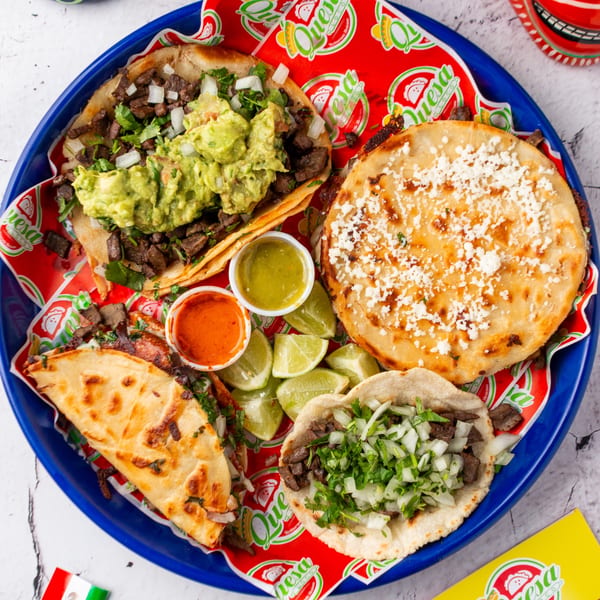A blue tray filled with various Quesa Loco Mexican dishes, including tacos, quesadillas, and salsas.