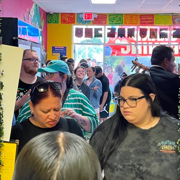 A crowded Quesa Loco restaurant with patrons waiting in line, colorful decor, and a mariachi musician.