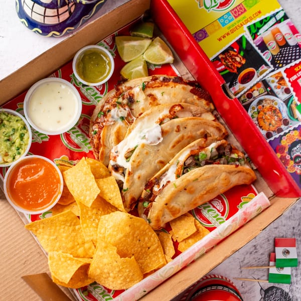 Quesa Loco's birria tacos, chips, guacamole, salsa, and queso in a takeout box.