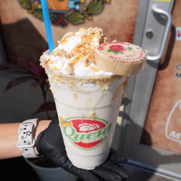 A Quesa Loco milkshake topped with whipped cream, caramel, crumbles, and a De La Rosa candy.