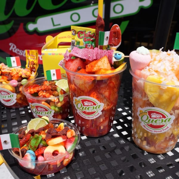 Multiple Quesa Loco cups and bowls filled with colorful Mexican street food, candies, and fruit.